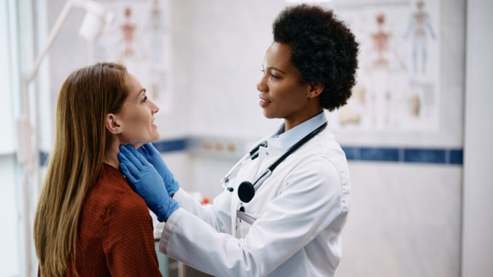 Doctor feeling womans throat during exam